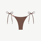 Praia Bottom in brown with adjustable tie sides, adorned with a pink and a beige bead on the left string, crafted from recycled polyamide for an eco-friendly swimwear option, shown on a white background.