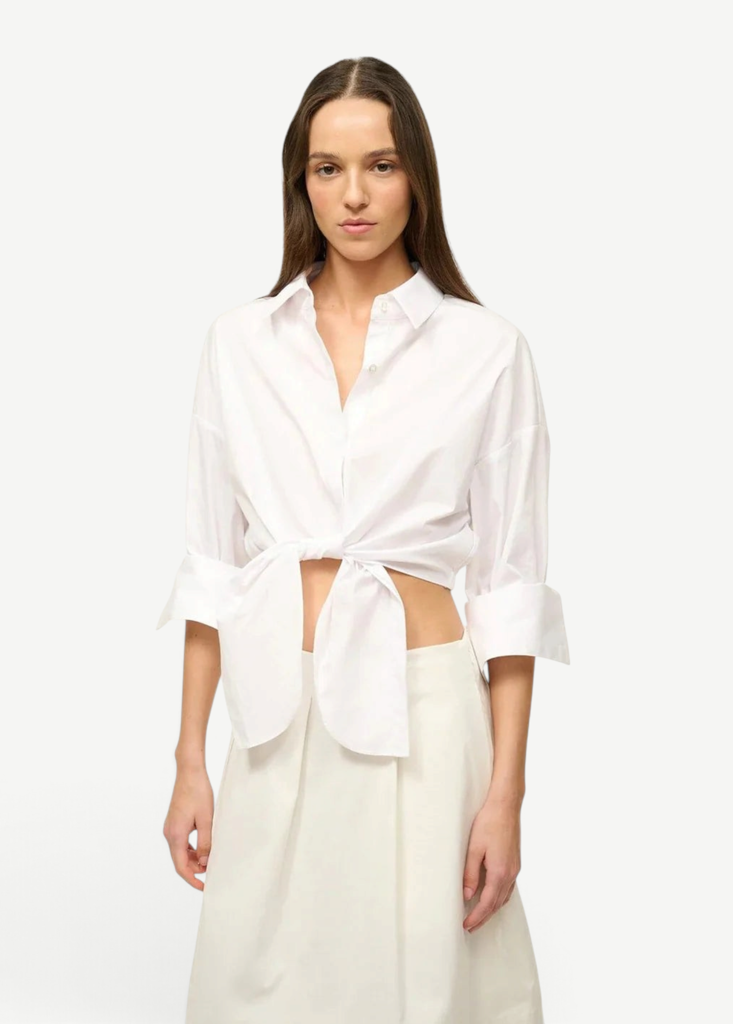A woman wears a white Lisa Top, a button-down cropped shirt with three-quarter length sleeves and a front-tie waist, styled for everyday dressing.