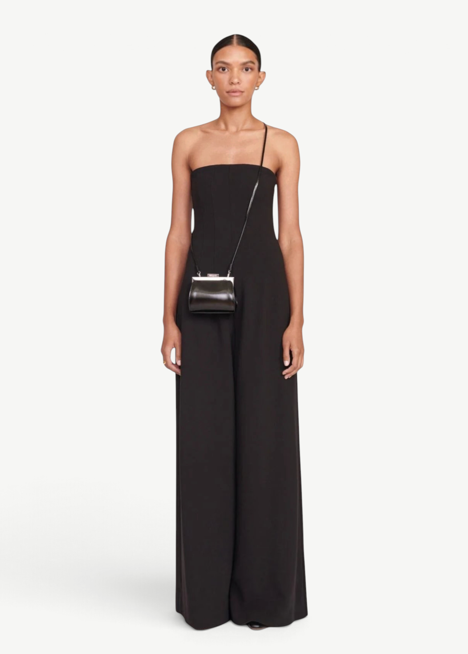 Model wearing a KABE SHOP INC Lennon convertible black bag as a crossbody accessory with a matching black jumpsuit.