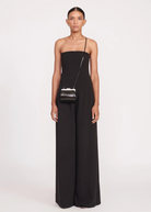 Model wearing a KABE SHOP INC Lennon convertible black bag as a crossbody accessory with a matching black jumpsuit.
