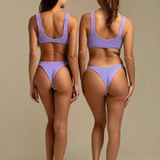 Two models wearing KABE SHOP INC Ginny bikini tops in textured lavender fabric, back view showing sporty silhouette.