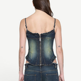 Back view of a person wearing a Denim Corset Top with a fitted, sculptural silhouette, featuring a center-back zipper and ruffle accents, paired with matching denim jeans.