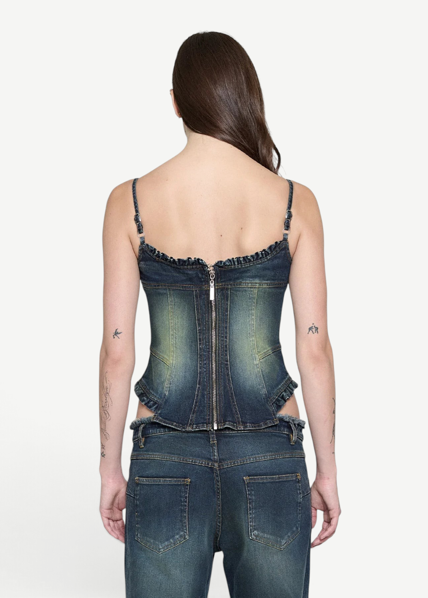 Back view of a person wearing a Denim Corset Top with a fitted, sculptural silhouette, featuring a center-back zipper and ruffle accents, paired with matching denim jeans.