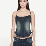Denim Corset Top in dark wash denim with thin straps and ruffled trim along the neckline and hem, creating a sculptural silhouette.
