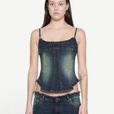 Denim Corset Top in dark wash denim with thin straps and ruffled trim along the neckline and hem, creating a sculptural silhouette.