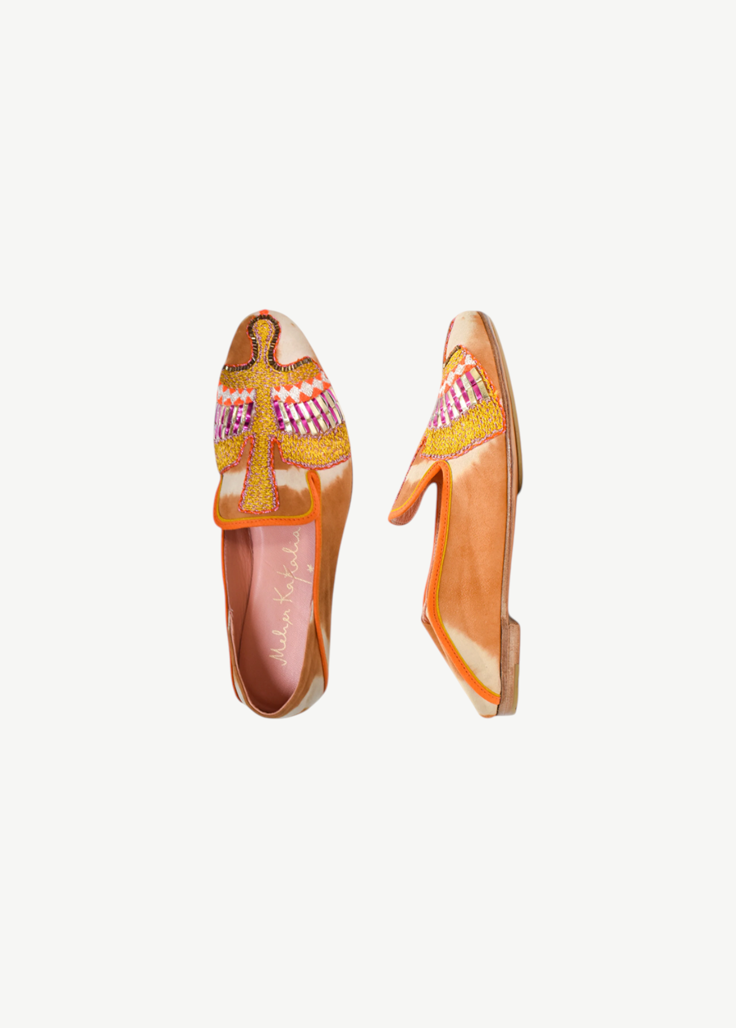 Two orange Anzu Moccasins featuring intricate pink, yellow, and gold beaded embroidery on the uppers are displayed side by side on a white background. These hand-embroidered moccasins showcase artful craftsmanship and style, making them a unique statement piece.