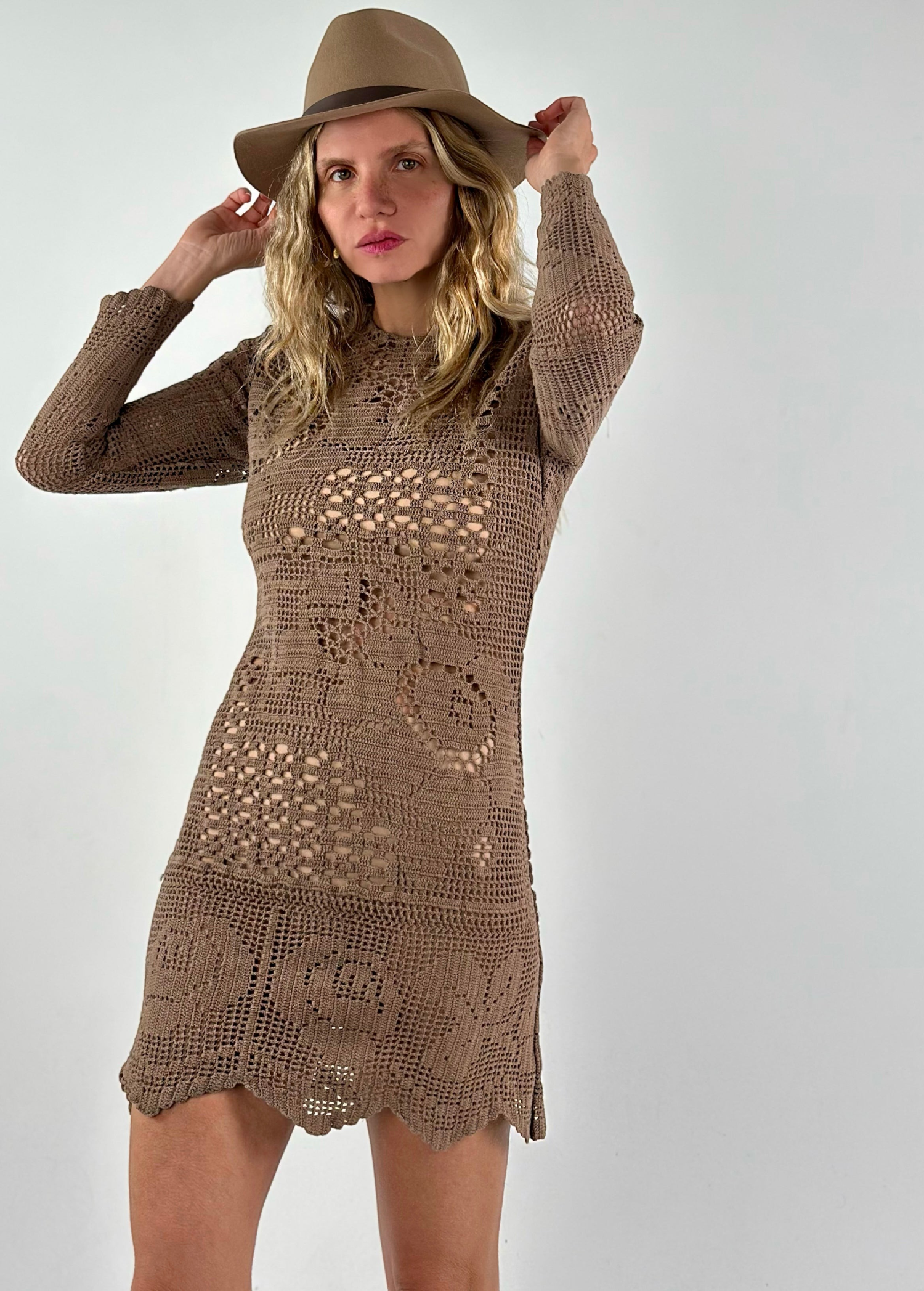 Model wearing a KABE SHOP INC long-sleeve brown crochet mini dress with intricate handwoven patterns and a fedora hat.
