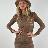 Model wearing a KABE SHOP INC long-sleeve brown crochet mini dress and a matching fedora hat against a white wall.