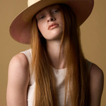 KABE SHOP INC Awisqa hat featuring a natural straw crown and wide pink brim worn by a model with long red hair