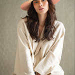 Model wearing a KABE SHOP INC Awisqa hat with a natural straw crown and pink brim, styled with a beige linen outfit.