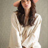 Model wearing a KABE SHOP INC Awisqa hat with a natural straw crown and pink brim, styled with a beige linen outfit.