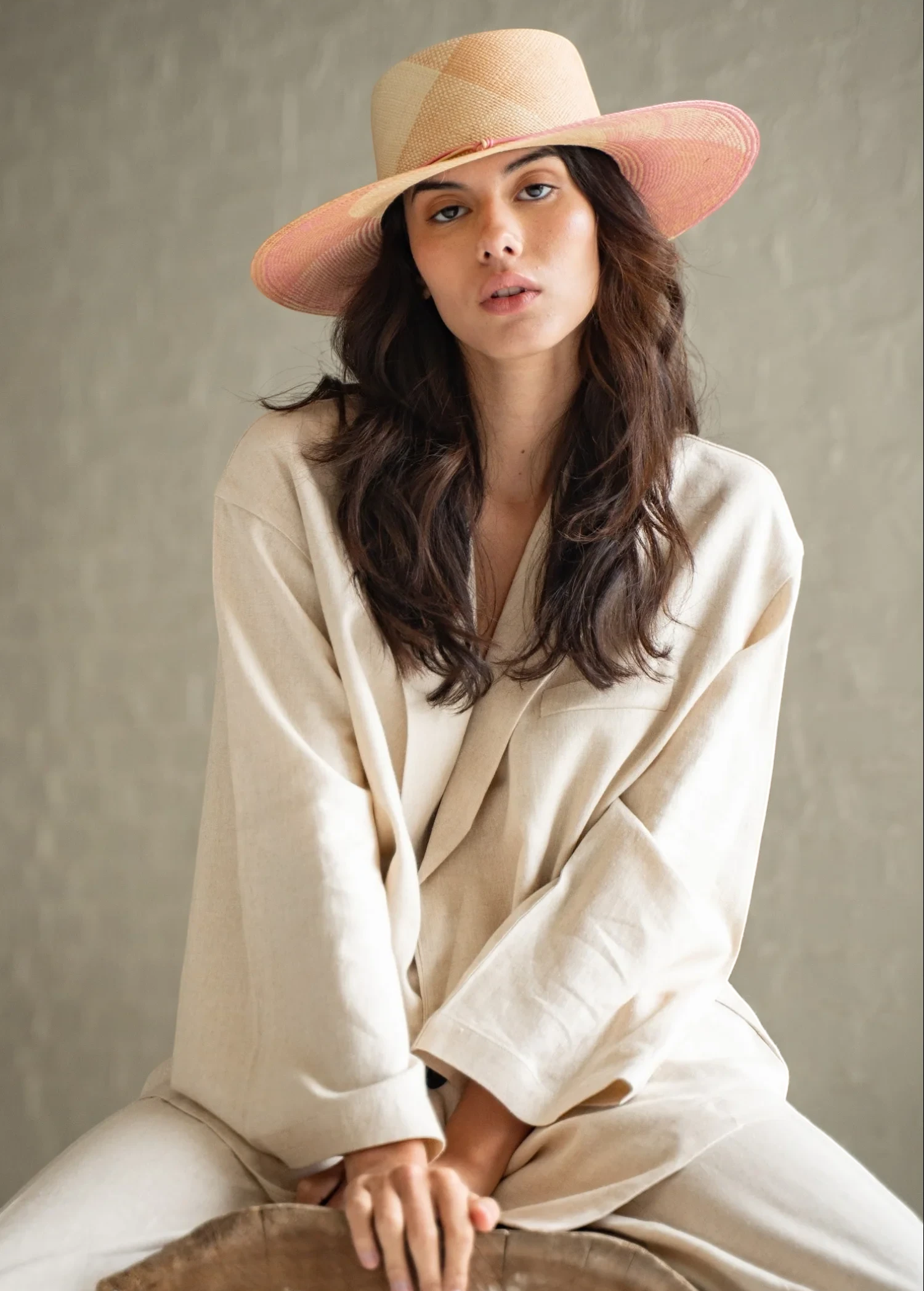 Model wearing a KABE SHOP INC Awisqa hat with a natural straw crown and pink brim, styled with a beige linen outfit.