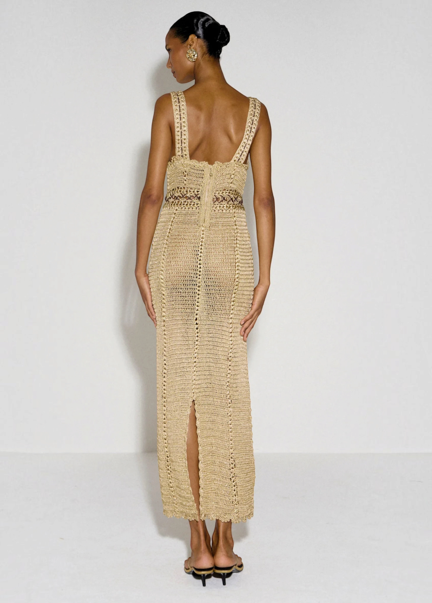 Model wearing a beige KABE SHOP INC crochet maxi dress with a halter neckline and back slit, viewed from behind.