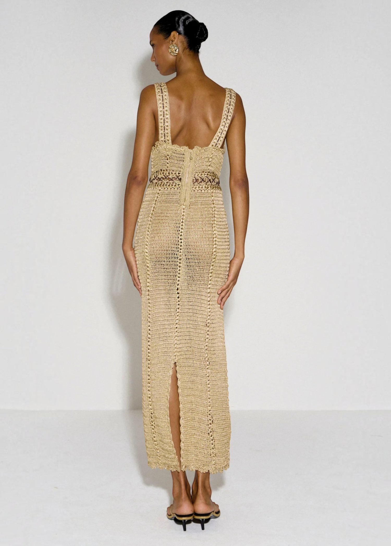 Model wearing a beige KABE SHOP INC crochet maxi dress with a halter neckline and back slit, viewed from behind.