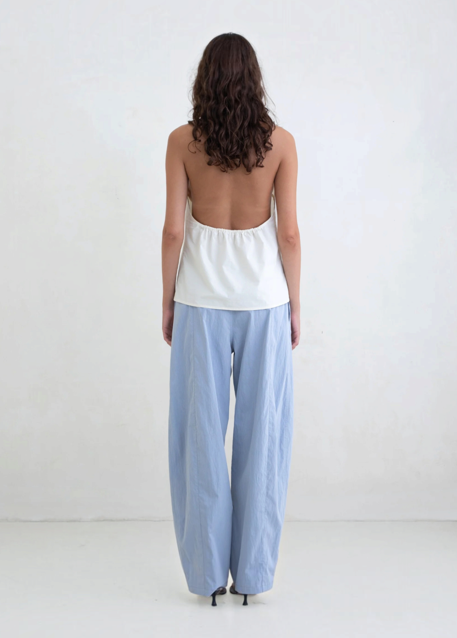 Model wearing KABE SHOP INC Breezy Pant, a light blue straight-leg trouser with a relaxed fit, back view.