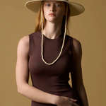 Model wearing a KABE SHOP INC Cajas wide brim straw hat with beaded chin strap against a tan background.
