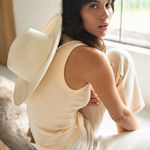 KABE SHOP INC Cajas wide brim straw hat worn by a woman in a cream tank top and trousers in a bright indoor setting