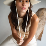 KABE SHOP INC Cajas wide brim straw hat in cream with a beaded chin strap worn by a woman in a neutral outfit