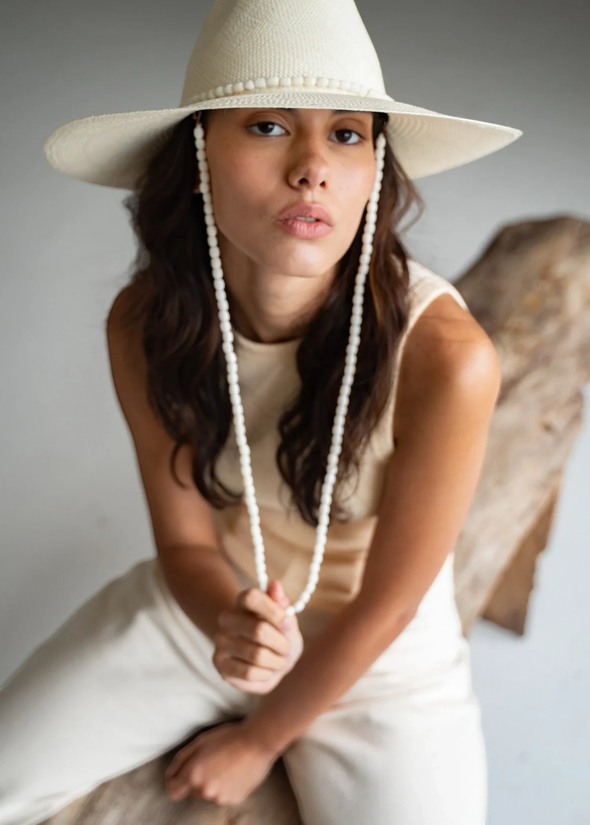 KABE SHOP INC Cajas wide brim straw hat in cream with a beaded chin strap worn by a woman in a neutral outfit