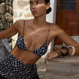 Model wearing KABE SHOP INC Calypso triangle bikini top in black and white abstract print with wooden bead accents