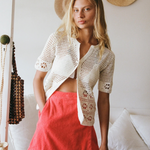 Model wearing a KABE SHOP INC Dolce skirt in bright coral pink paired with a white crochet cardigan