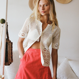 Model wearing a KABE SHOP INC Dolce skirt in bright coral pink paired with a white crochet cardigan