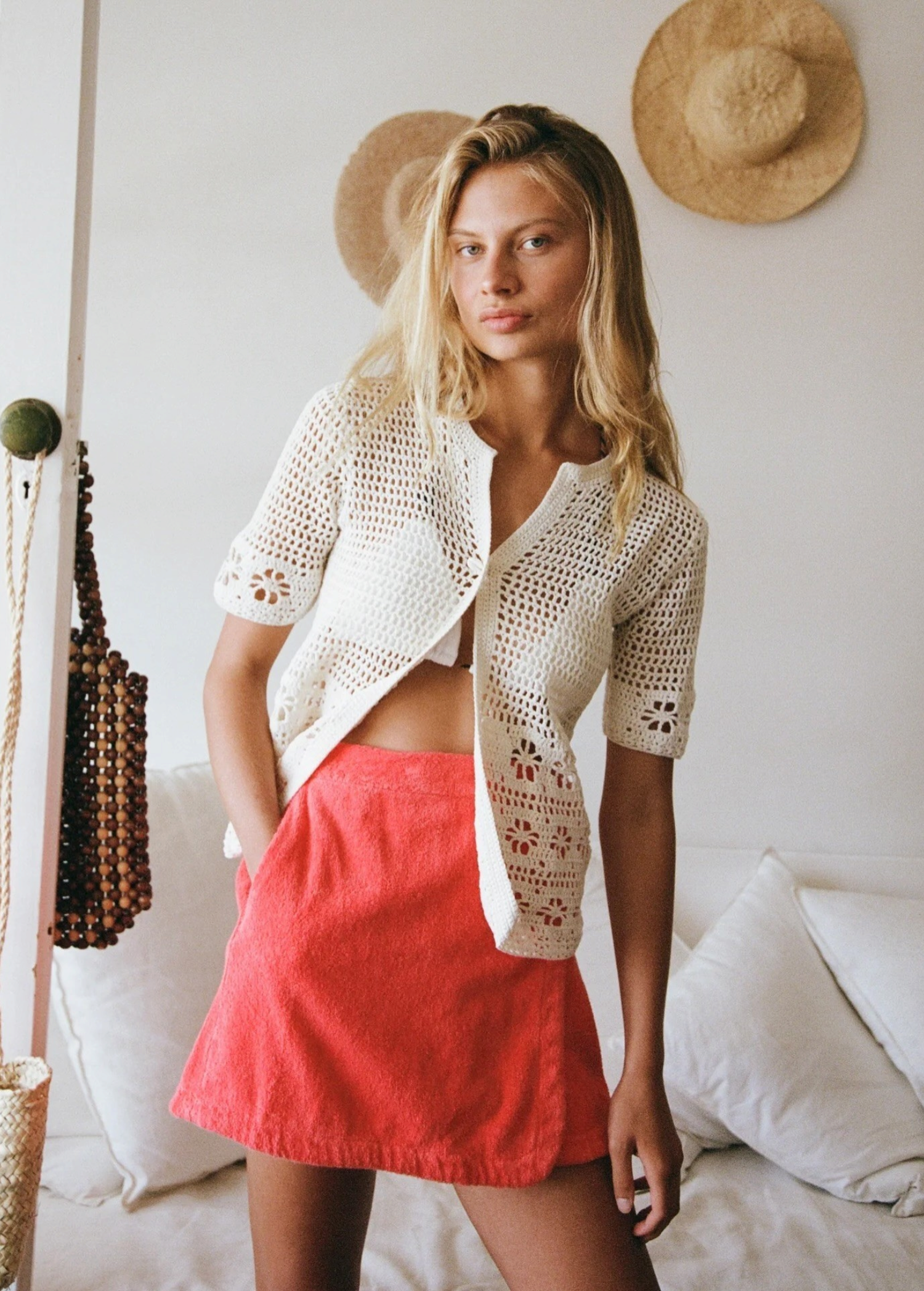 Model wearing a KABE SHOP INC Dolce skirt in bright coral pink paired with a white crochet cardigan