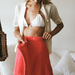 KABE SHOP INC Dolce skirt in bright red worn by a woman with a white crochet cardigan and bikini top