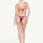 Model wearing KABE SHOP INC Equator triangle bikini top and matching bottom in burgundy paisley print from behind.