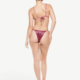 Model wearing KABE SHOP INC Equator triangle bikini top and matching bottom in burgundy paisley print from behind.