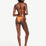 Model wearing KABE SHOP INC Equator Top, an orange triangle bikini top with adjustable straps, back view.