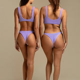 Two models wearing KABE SHOP INC Ginny bikini tops in textured lavender fabric, back view showing sporty silhouette.