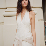 KABE SHOP INC Helia white halter gown with a plunging neckline and open back worn by a model outdoors