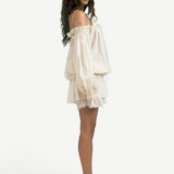 Model wearing a KABE SHOP INC Isabella cotton jumpsuit in cream with off-the-shoulder sleeves and delicate lace trim.