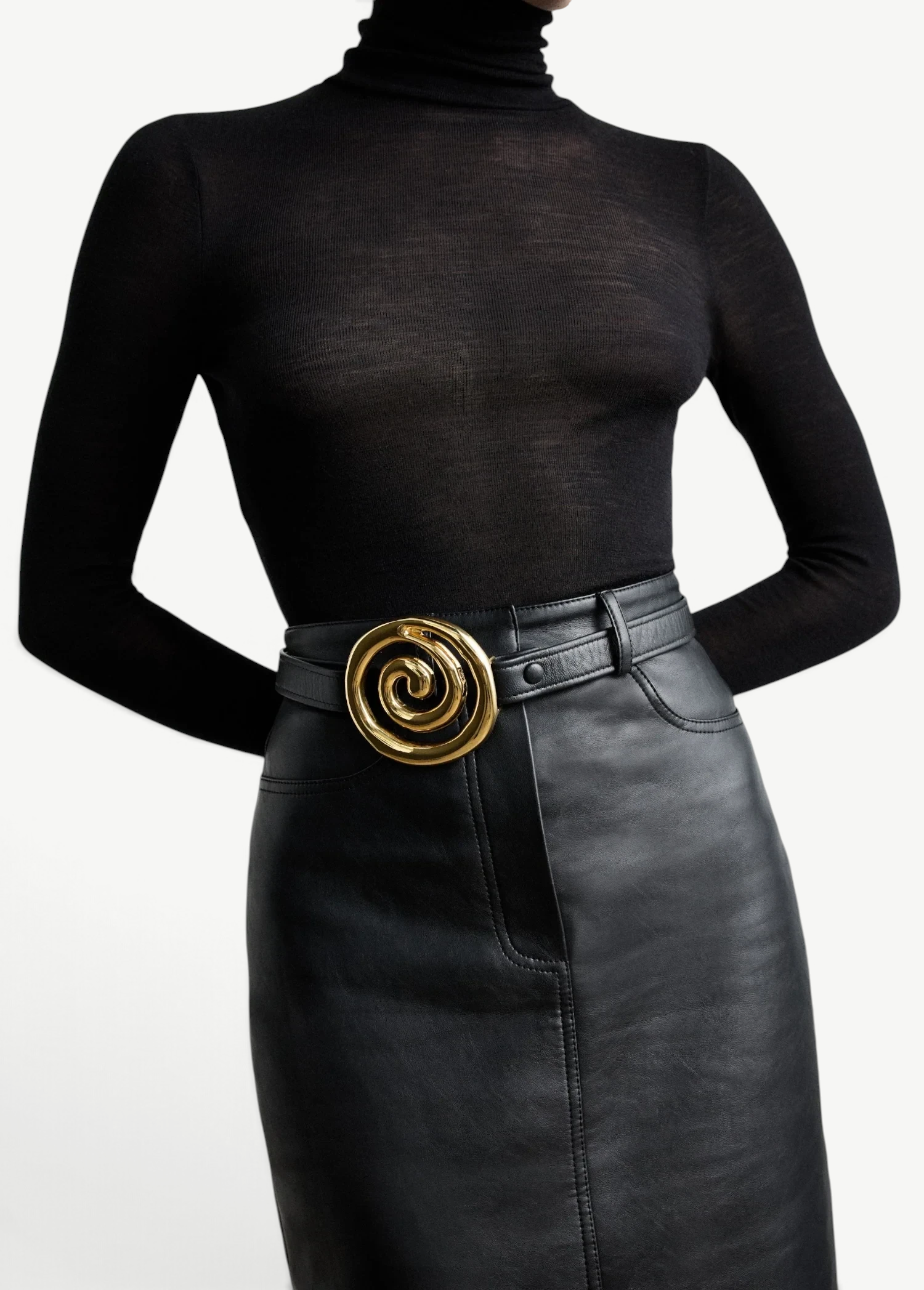 KABE SHOP INC Koru belt in black Italian calfskin with a sculptural gold spiral buckle worn over a black skirt
