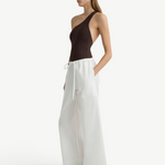 Model wearing KABE SHOP INC white Kyoto wide leg cotton pants with a brown one-shoulder bodysuit and black sandals.