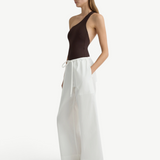 Model wearing KABE SHOP INC white Kyoto wide leg cotton pants with a brown one-shoulder bodysuit and black sandals.