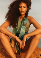 KABE SHOP INC Magdalena Pareo with a fluid landscape print worn as a halter top by a woman at sunset
