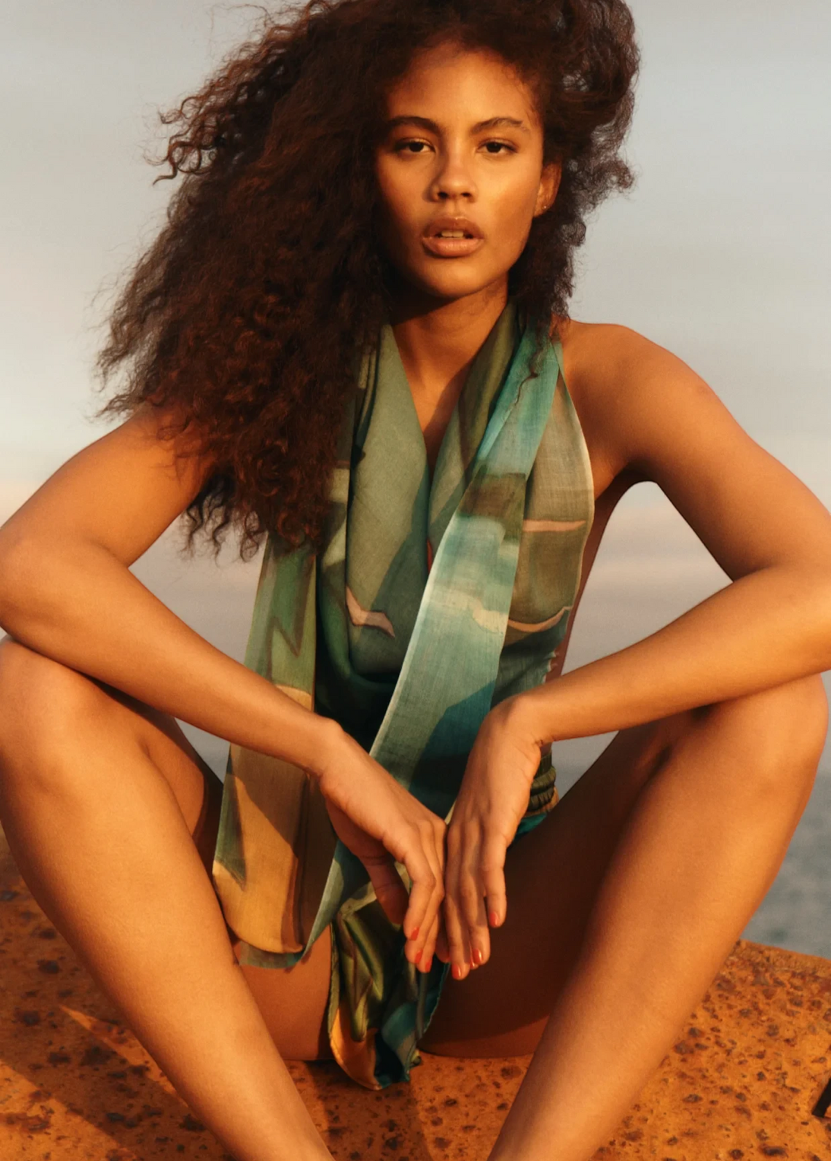 KABE SHOP INC Magdalena Pareo with a fluid landscape print worn as a halter top by a woman at sunset