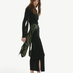 Model wearing KABE SHOP INC Maltha midi skirt in black with a green patterned wrap detail and side slit