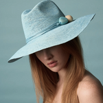 KABE SHOP INC Mayu hat in light blue woven straw with decorative bead accents worn by a woman