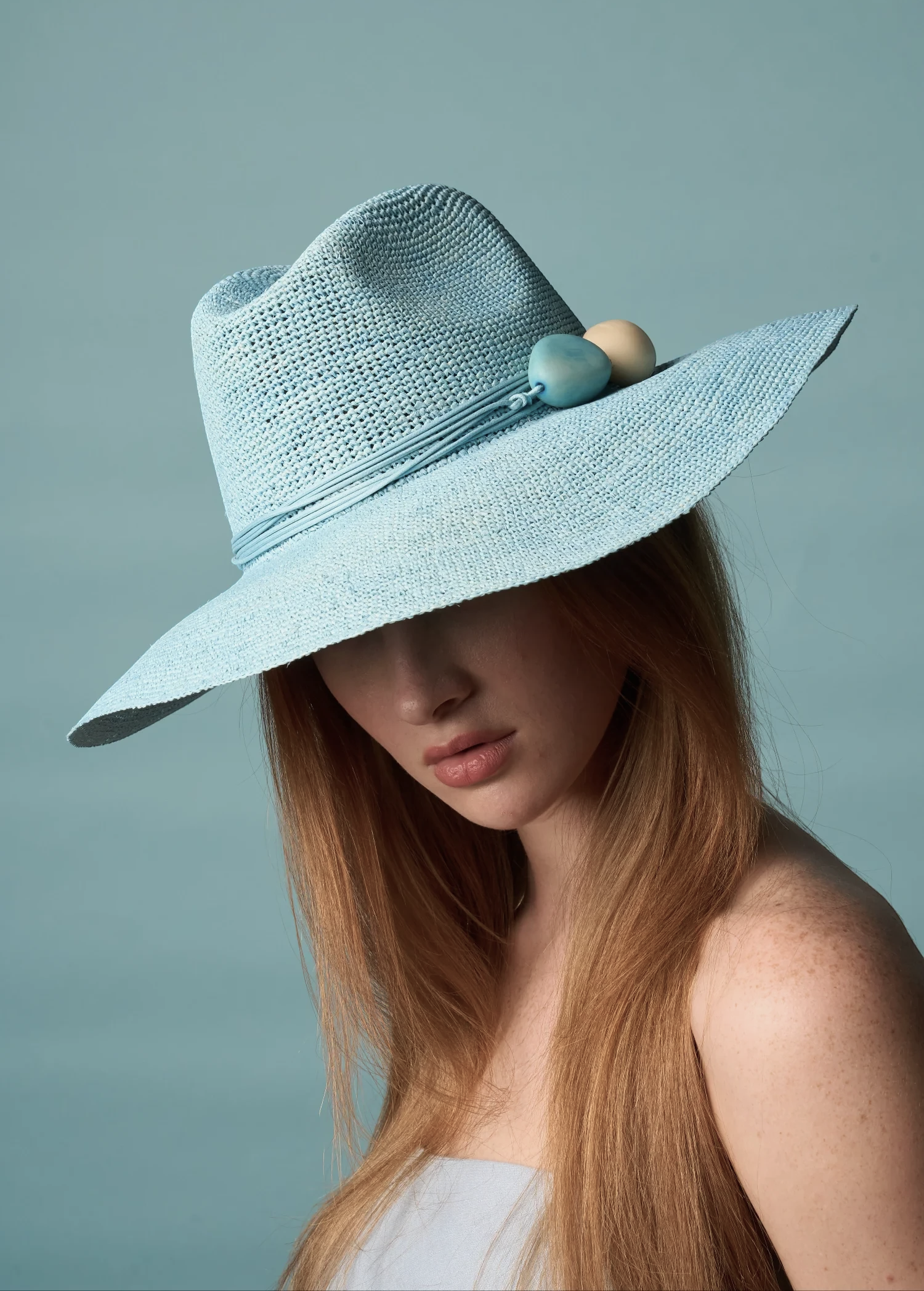 KABE SHOP INC Mayu hat in light blue woven straw with decorative bead accents worn by a woman