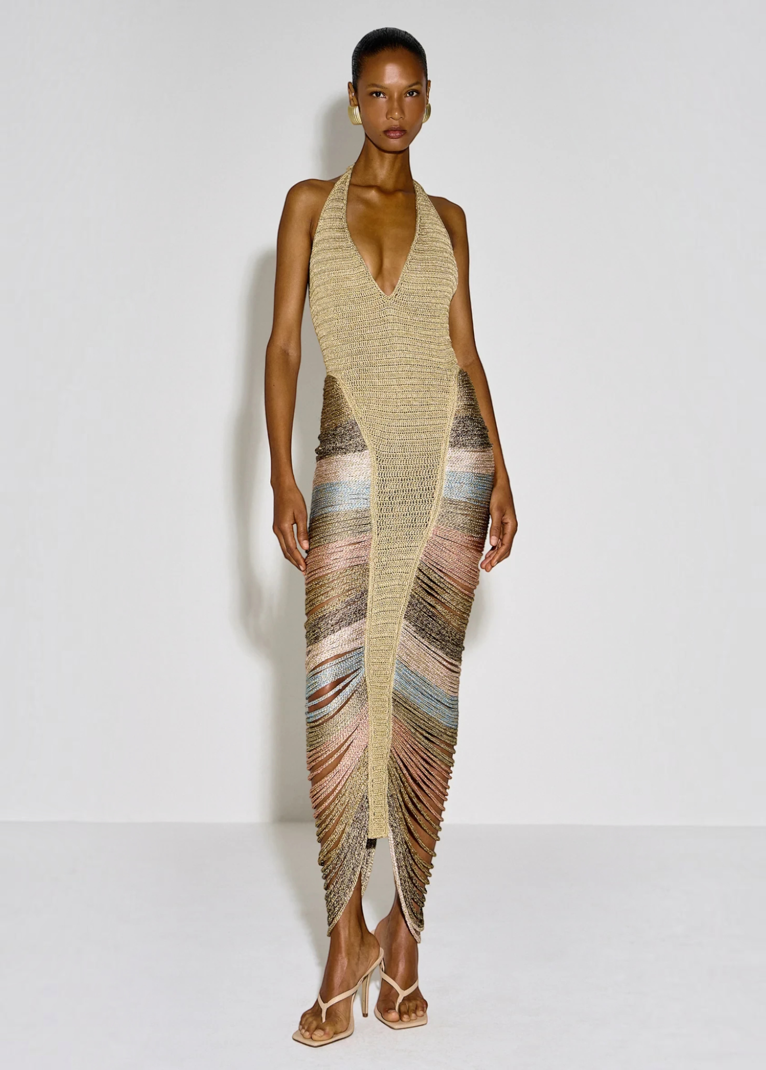 Model wearing KABE SHOP INC Melissa halter neck midi dress in metallic gold with multi-colored corded fringe detail.