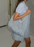 KABE SHOP INC Deiji Studios Chain Bag in metallic silver knit worn over the shoulder with a light blue dress