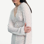 Model wearing a KABE SHOP INC sheer white Mirror Dress with delicate silver circular embellishments and long sleeves.