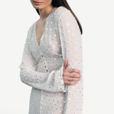 Model wearing a KABE SHOP INC sheer white Mirror Dress with delicate silver circular embellishments and long sleeves.
