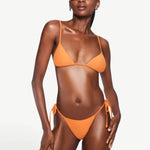 Model wearing KABE SHOP INC Equator Top, an orange triangle bikini top with adjustable straps and matching bottoms.