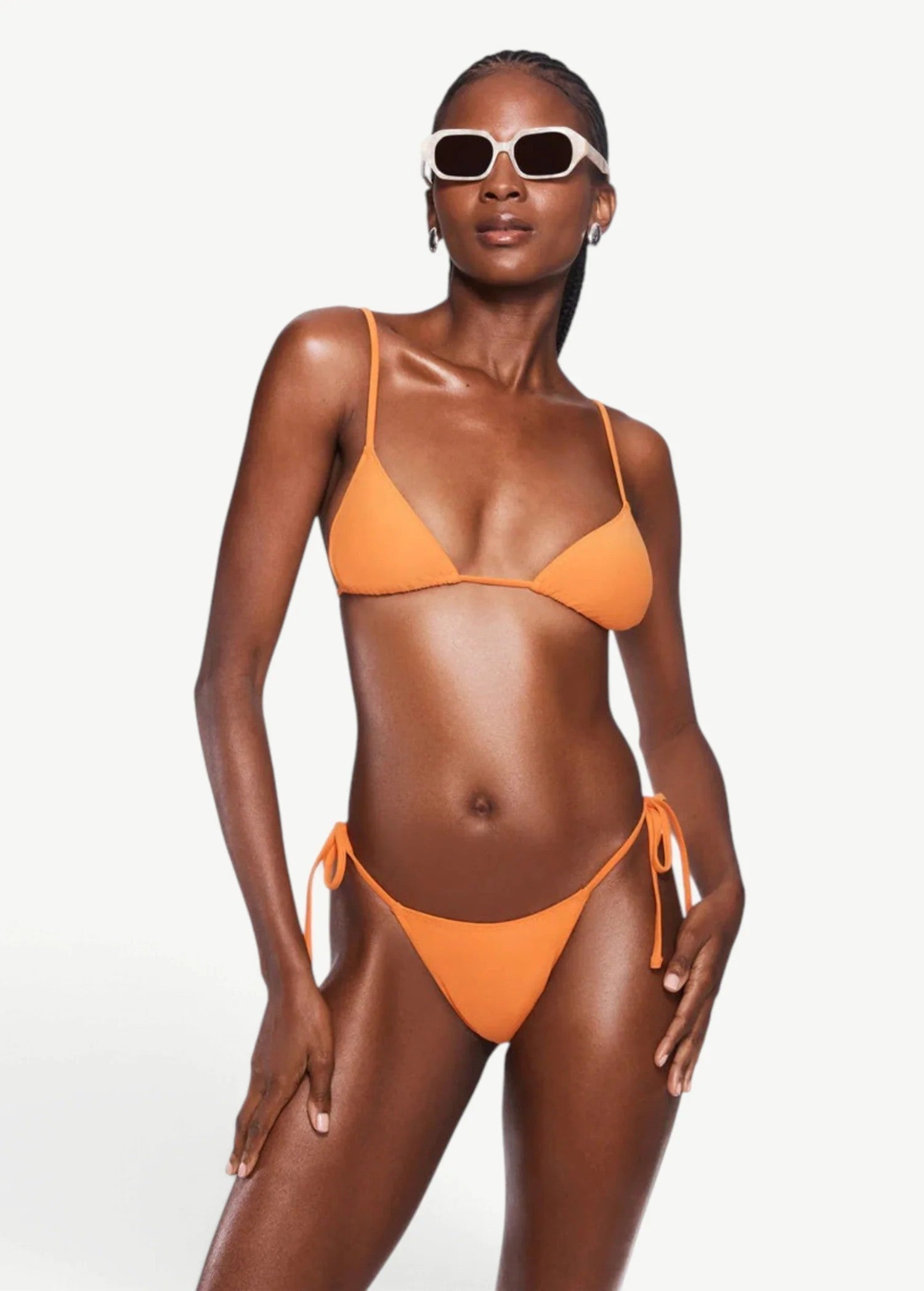 Model wearing KABE SHOP INC Equator Top, an orange triangle bikini top with adjustable straps and matching bottoms.