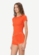 KABE SHOP INC model wearing orange terry cloth mini track shorts and a matching slim-fit ribbed t-shirt