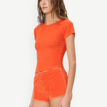 KABE SHOP INC model wearing orange terry cloth mini track shorts and a matching slim-fit ribbed t-shirt